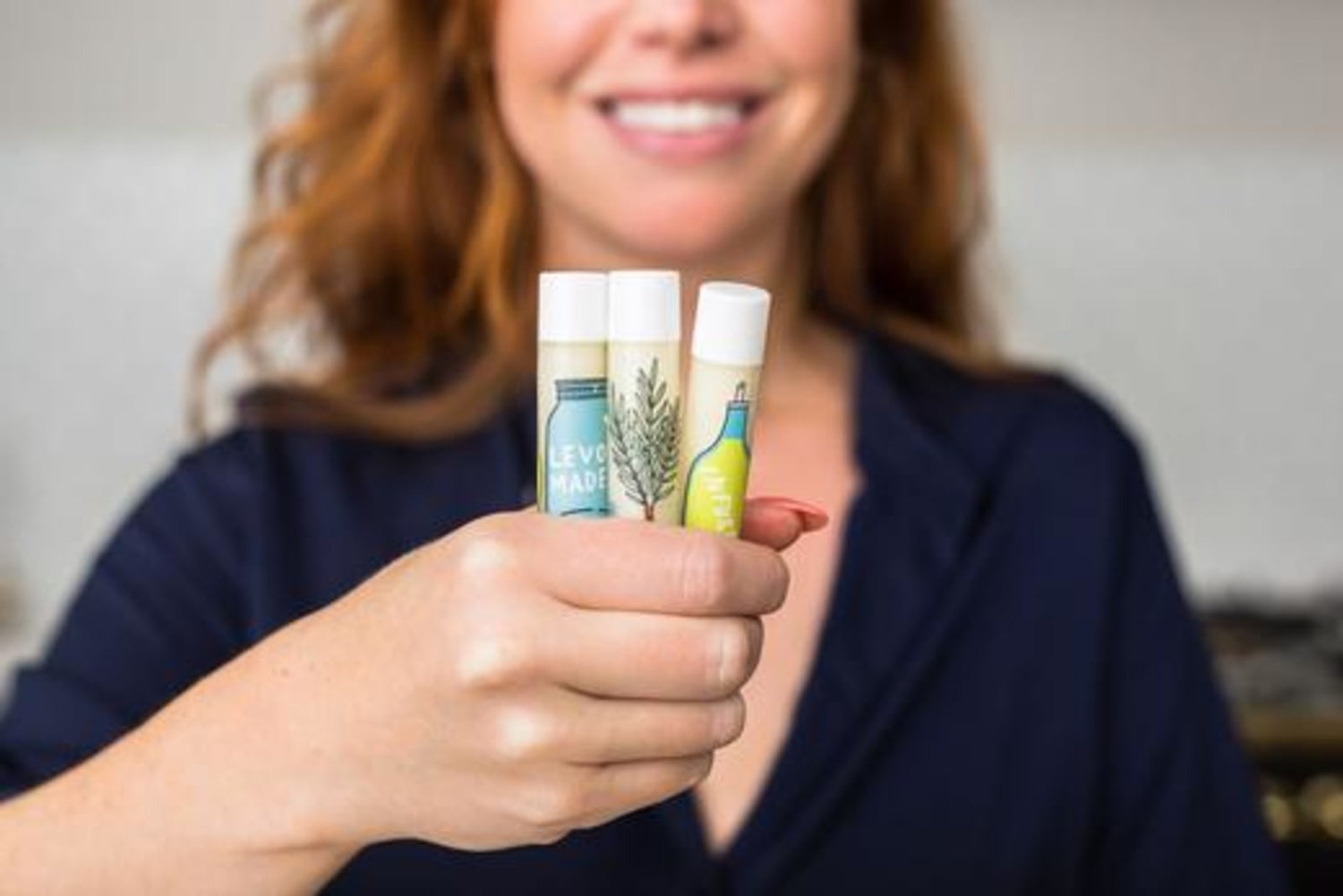 Image of woman holding homemade vegan lip balm, made by LEVO.