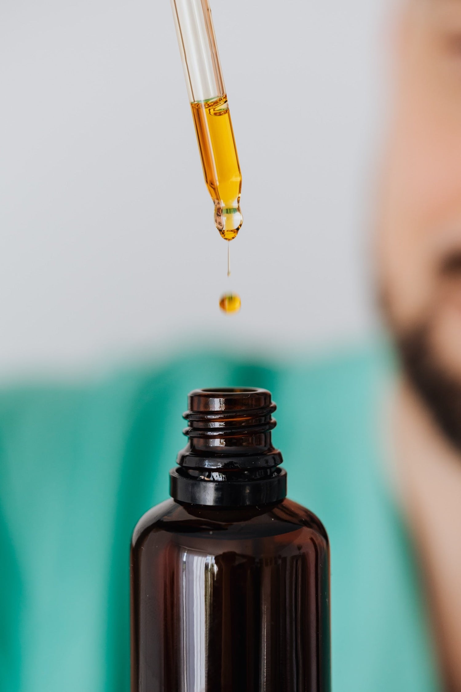 A person removes moisturizing beard oil from a LĒVO bottle to use on their beard.