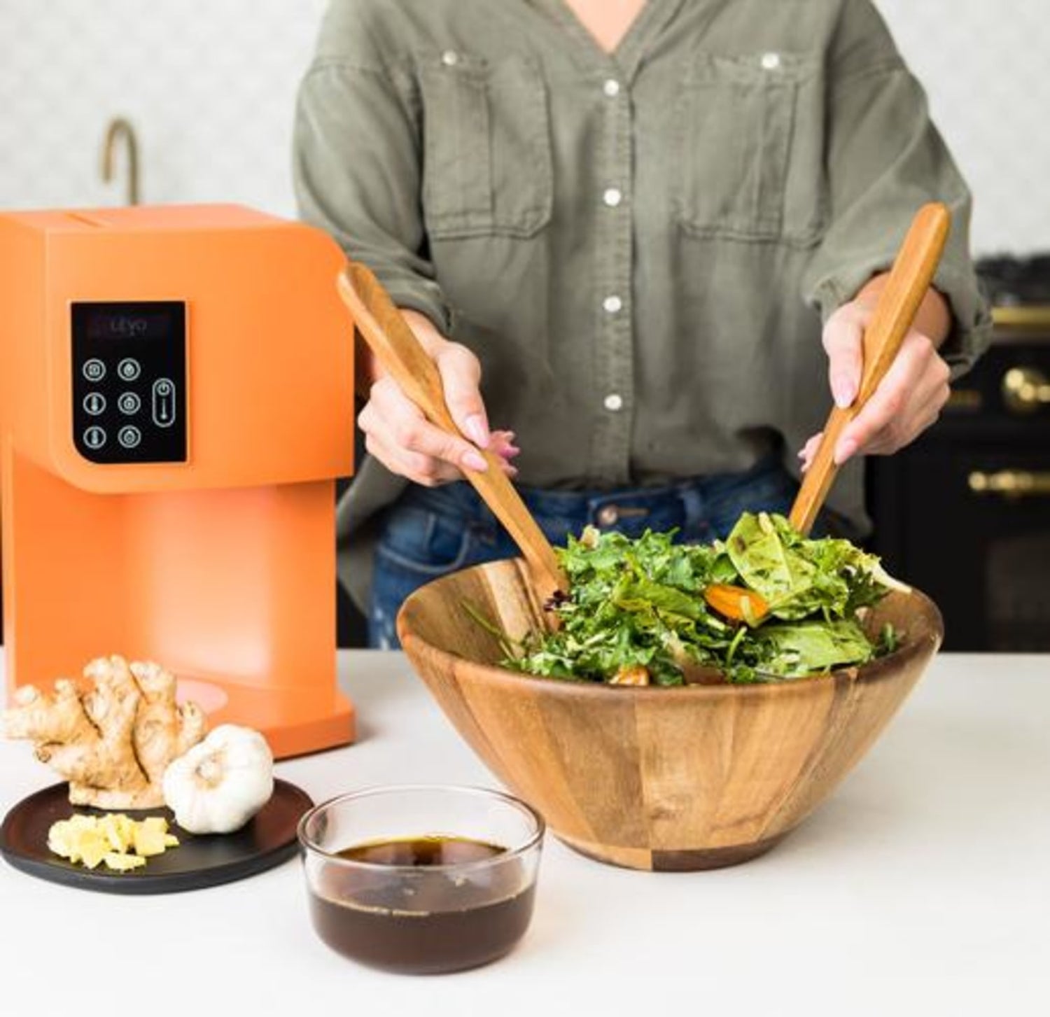 Image of a woman mixing a salad while following LEVO's recipe for sesame ginger salad dressing.