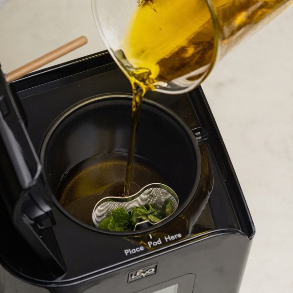 Pouring oil over herbs in the LĒVO II+ herb pod #Color_Licorice Black