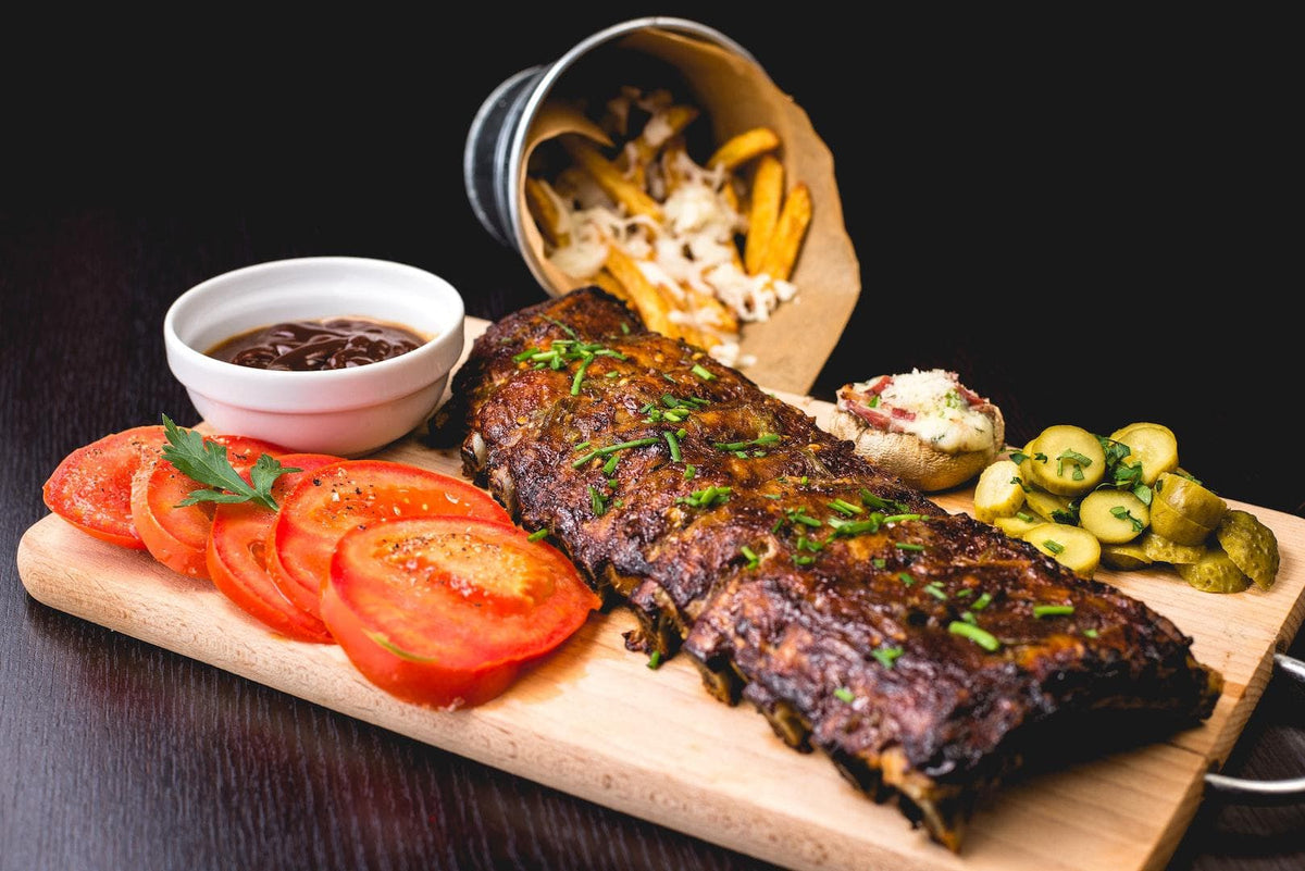 A plated rack of ribs with sliced tomatoes