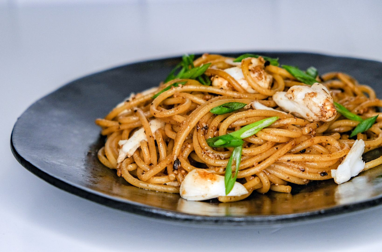 Image of a plate of garlic noodles with crab meat. Made by LĒVO.