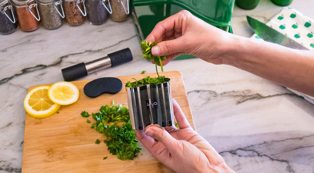 Image of a person adding herbs into the LĒVO herb pod for an herbal infusion.