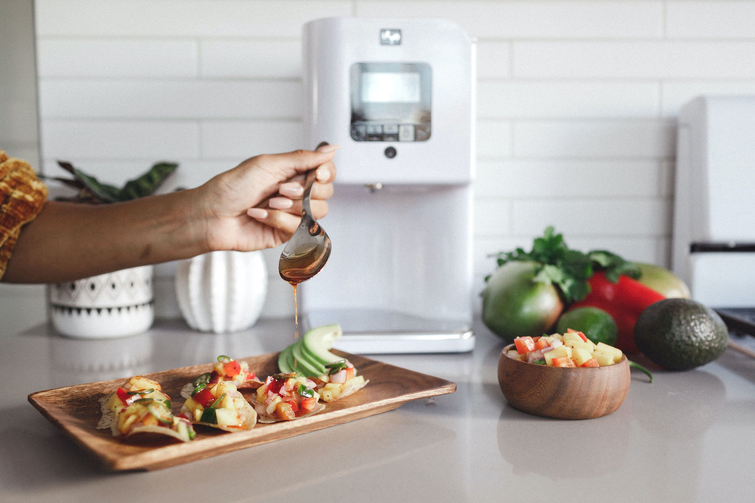 Image of a person pouring herbal infusions over tacos next to a LEVO II device.