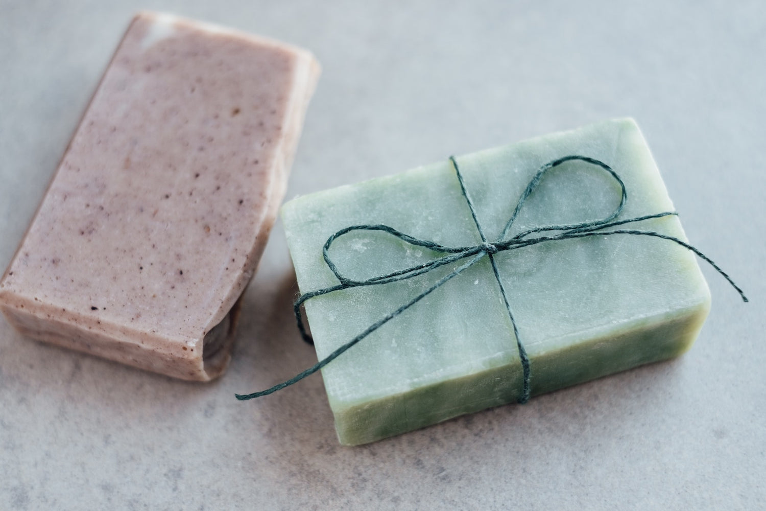 Image of a homemade handwashing soap wrapped in twine next to another homemade handwashing soap.