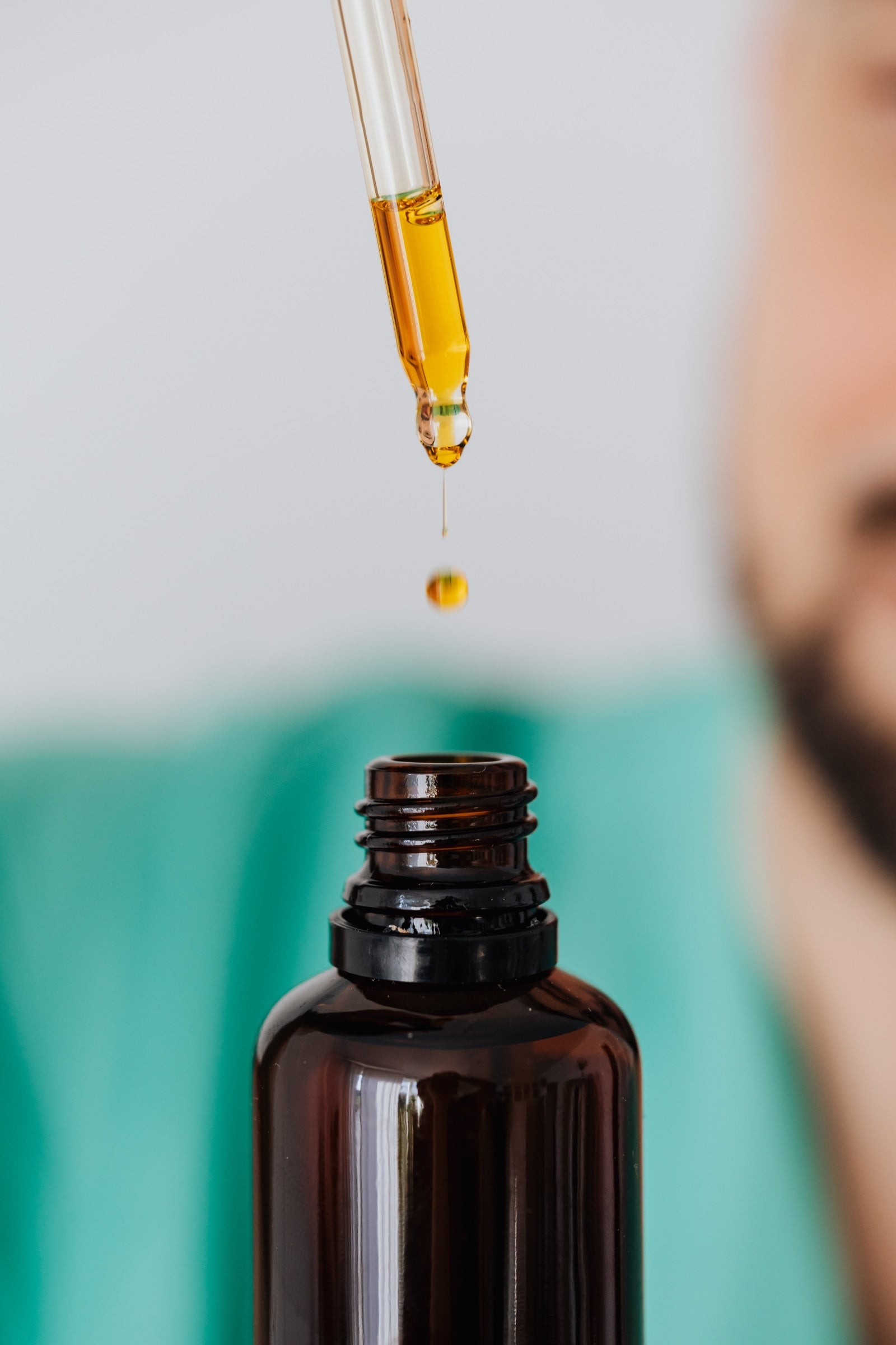 A person removes moisturizing beard oil from a LĒVO bottle to use on their beard.