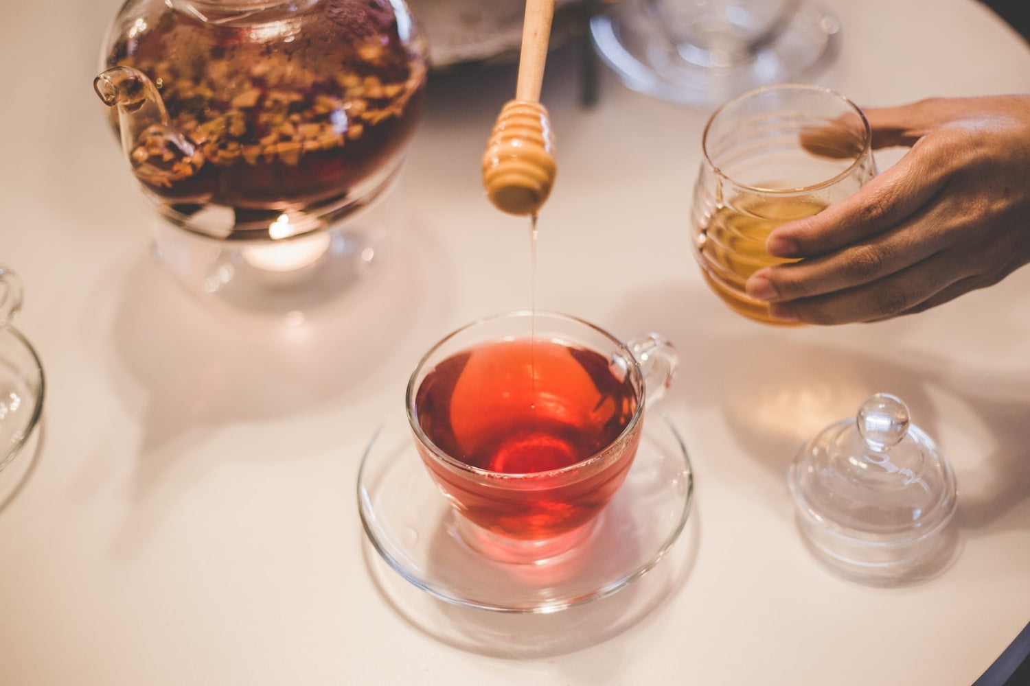 Person adding honey to tea in order to make LĒVO's DIY flu remedy.