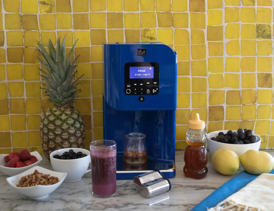 LĒVO II+ on a kitchen counter with honey and fresh fruit